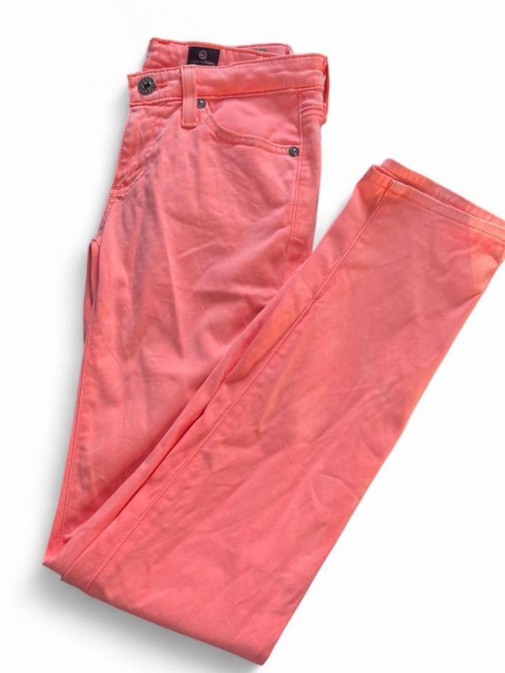 AG the stilt cigarette leg jeans in a bright neon orangey-peach/pink color.